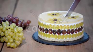 用刀子切<strong>慕斯</strong>蛋糕和葡萄。 用葡萄装饰的圆<strong>慕斯</strong>蛋糕。